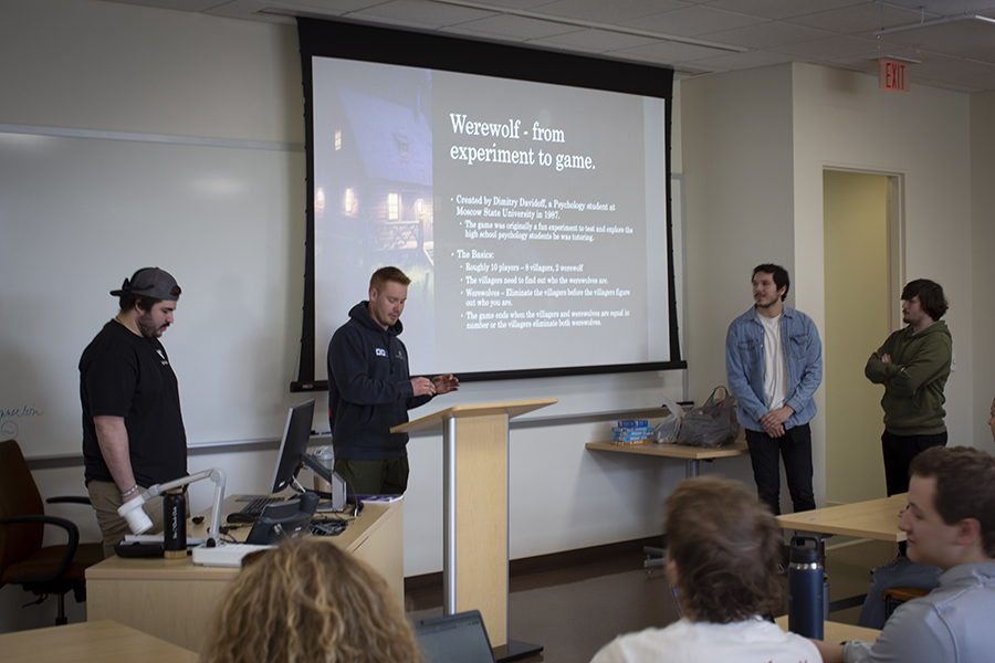 Four students stand at the front of class and present.