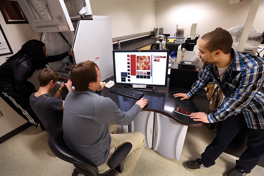 A group of students work around a computer.