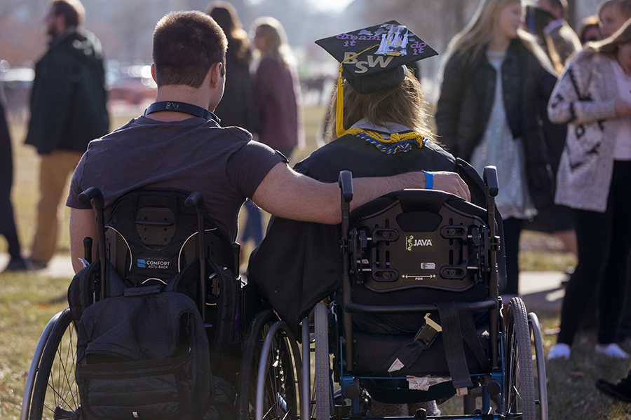 Two people in wheelchairs with their arms around each other.