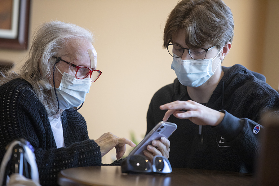 A student and a senior citizen look at a phone together.