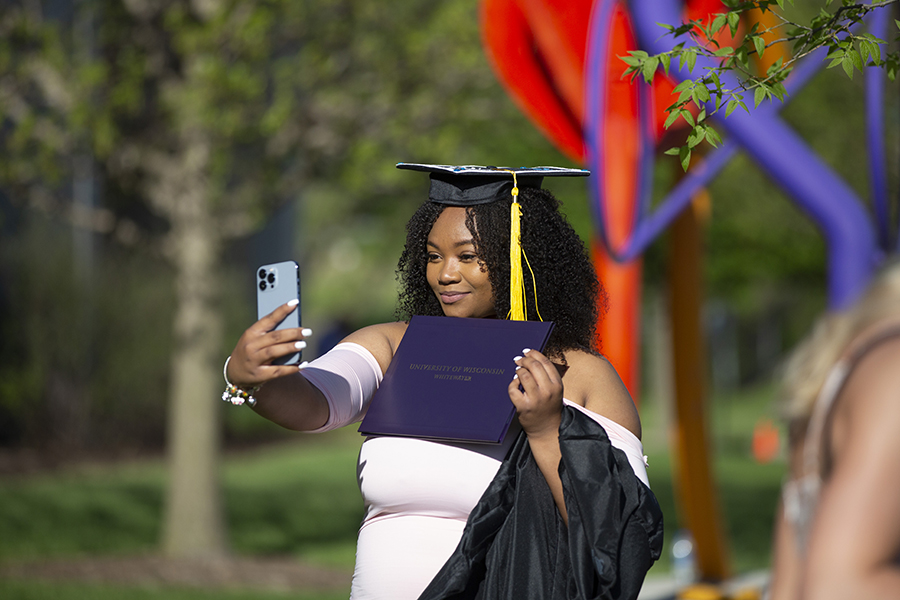 A student in a graduation cap takes a selfie.