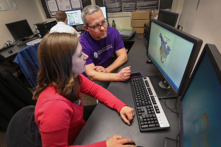 David Travis talks with a student in front of a weather poster.