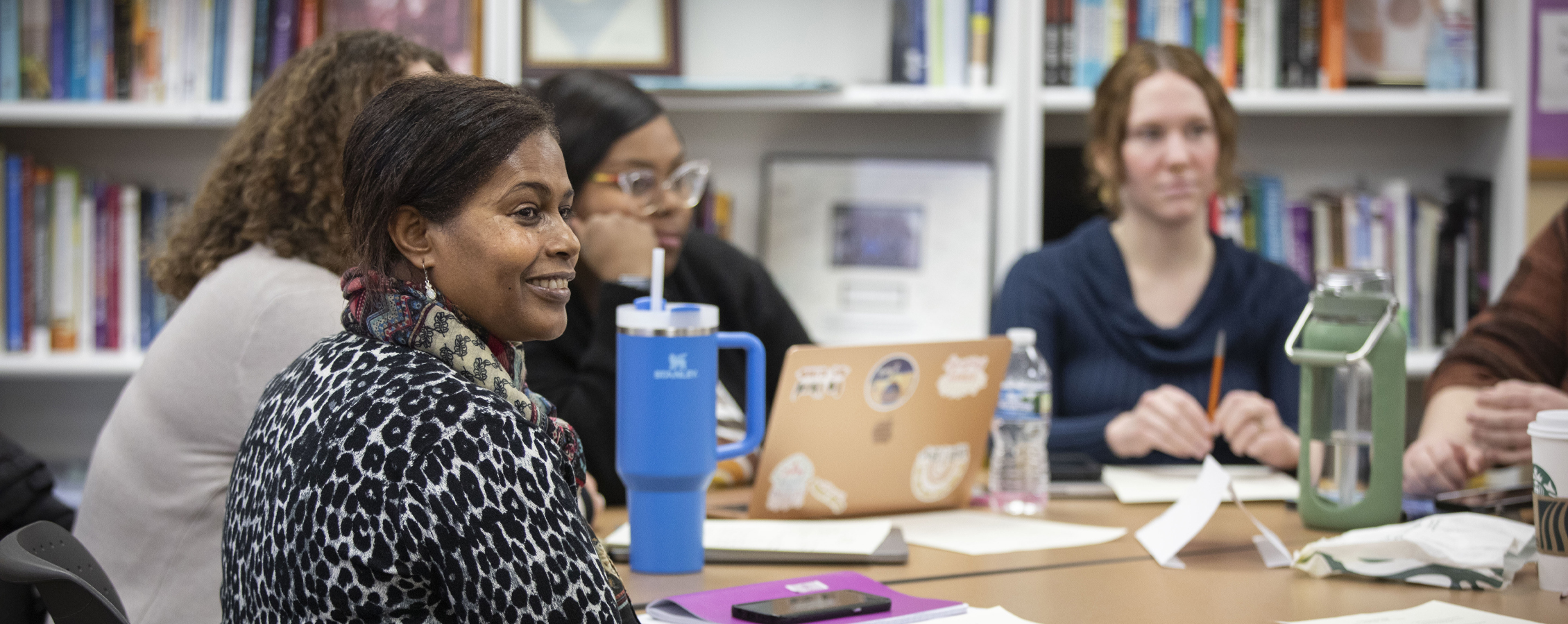 A person points at a large, printed report as another person looks on.