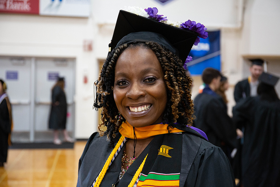 A person wearing academic regalia smiles at the camera.