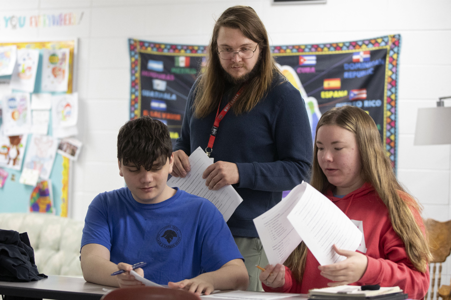 Middle school teacher assists students with project.