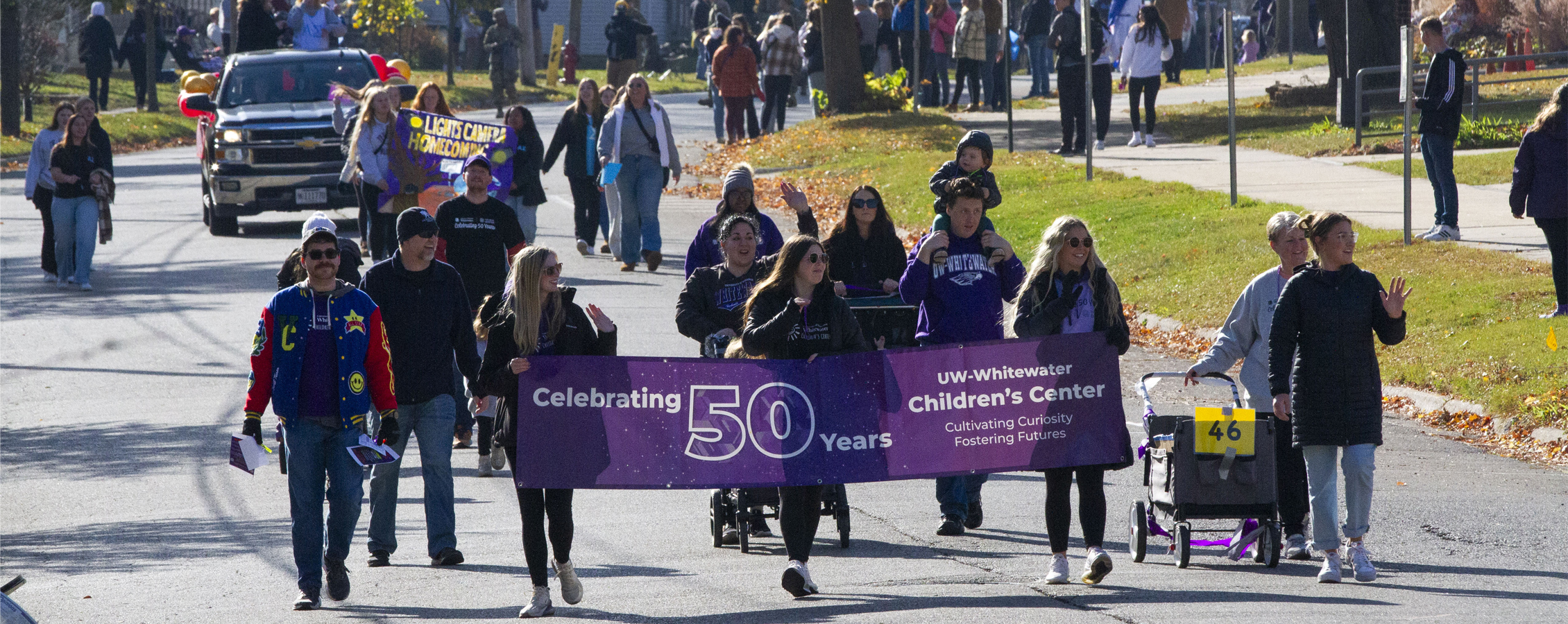 People march in a parade whle holding a sign that says Celebrating 50 Years. UW-Whitewater Children's Center.