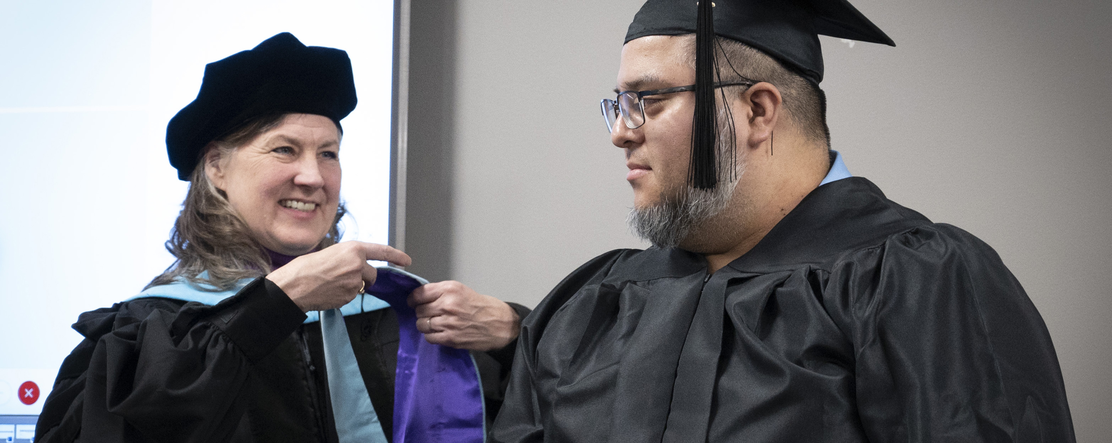 Lucy Heimer awards a student an academic hood.