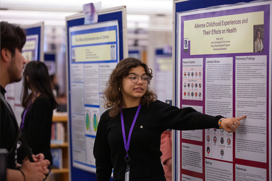 A student shares their research on a large board.