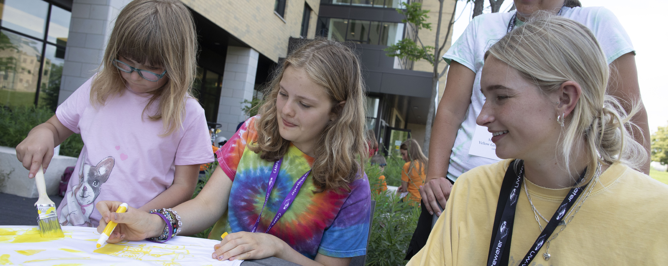 A graduate student works with children who are painting.