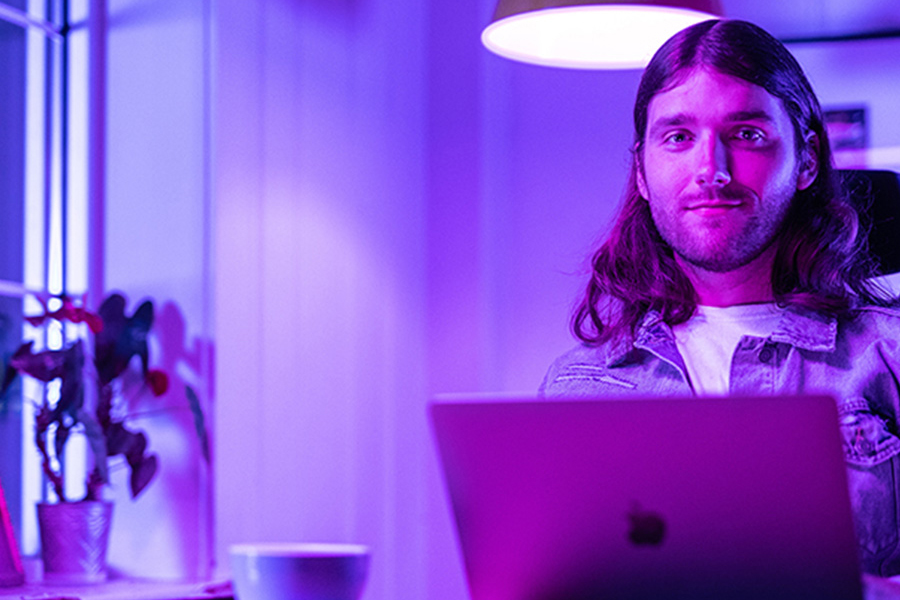 A person looks at the camera from behind a computer.