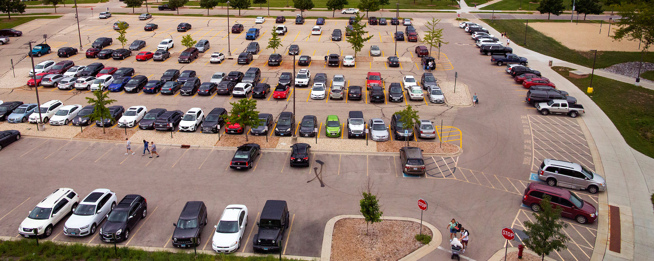 Aerial photo of a parking lot with many cars parked in spaces.