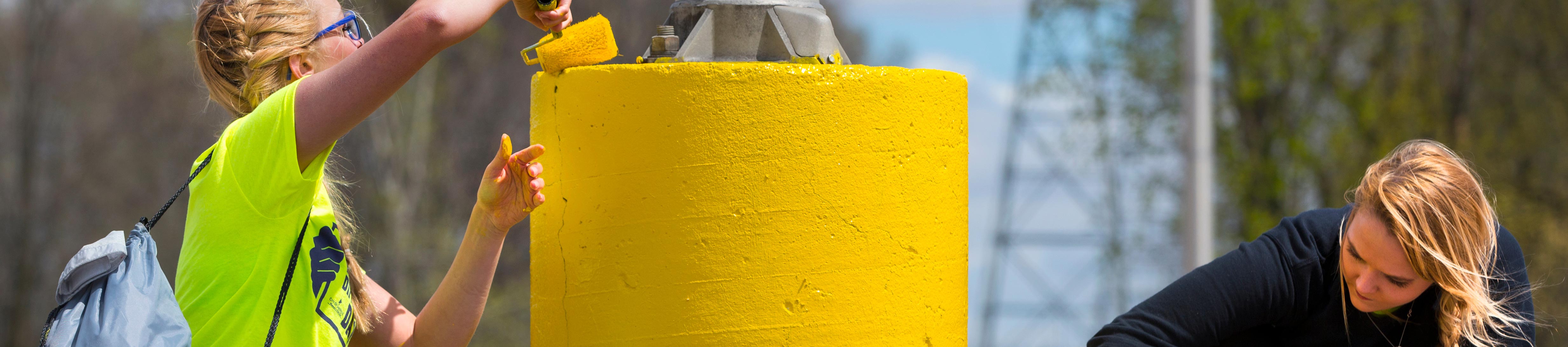 UW-Whitewater students painting a parking pylon