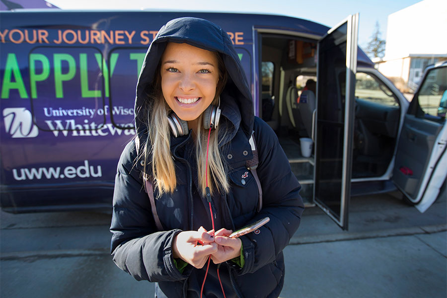 Student in front of shuttle bus.