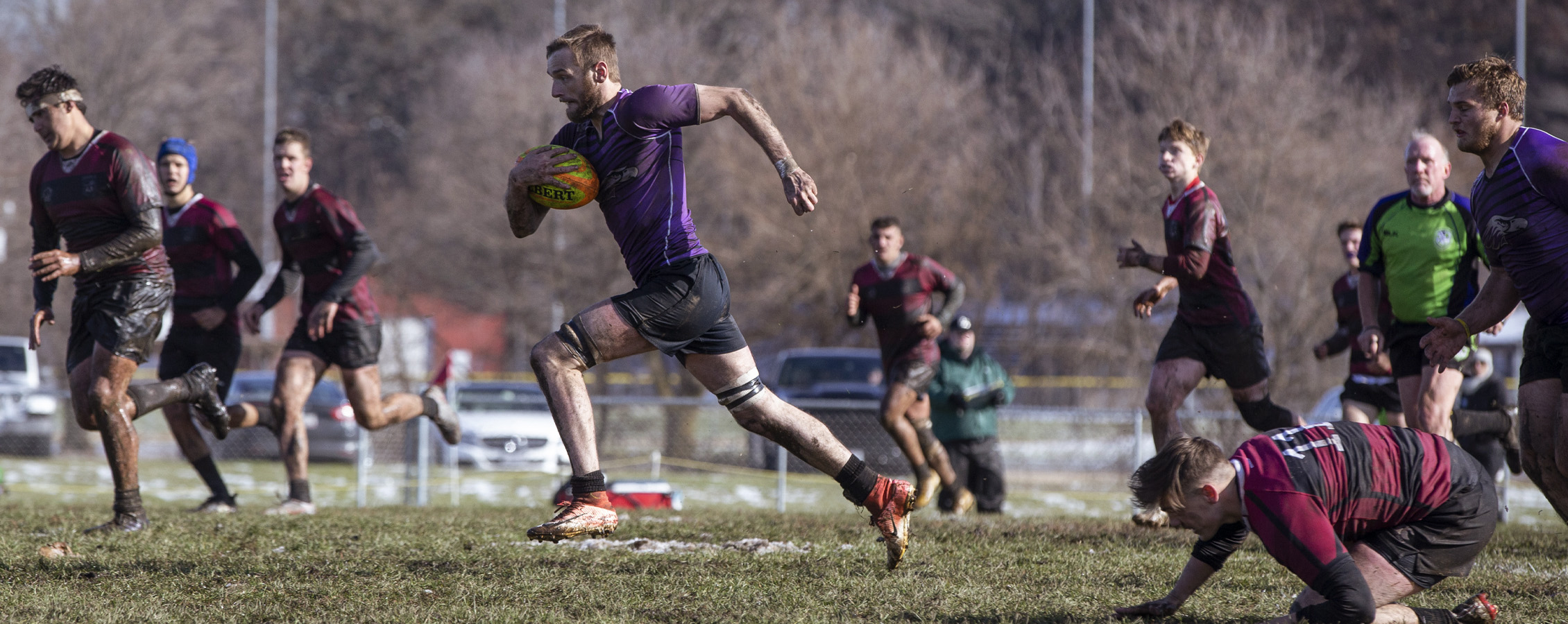 A Warhawk men's rugby player runs with the ball.