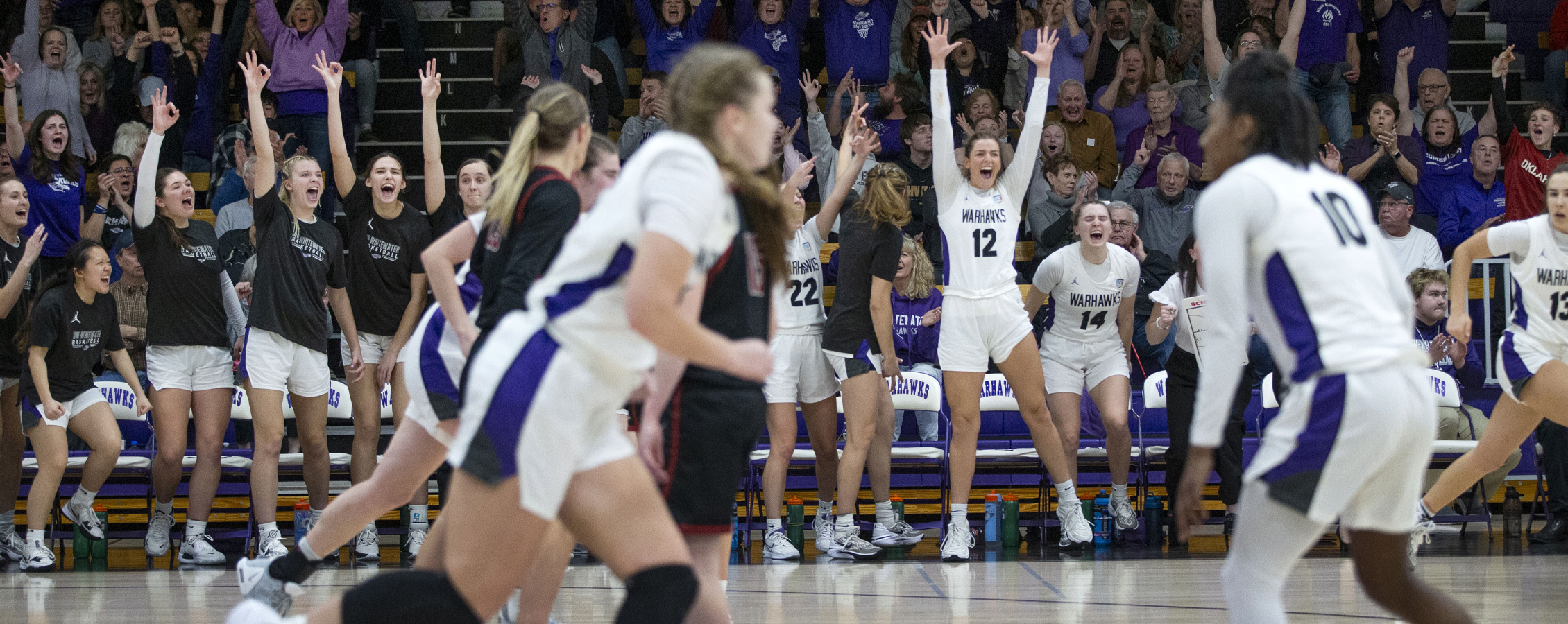 The women's basketball team jumps and cheers during a game.