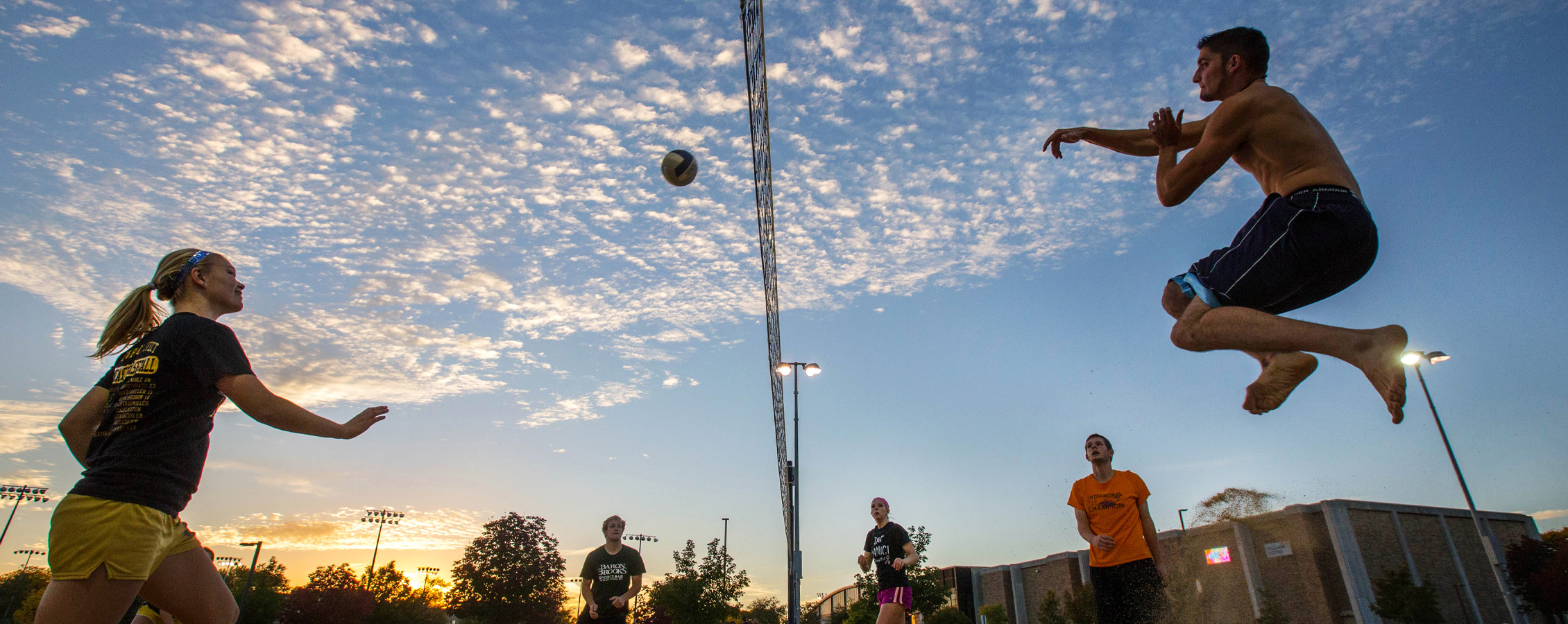 Two people on opposite sides of a volleyball net hit the ball back and forth.