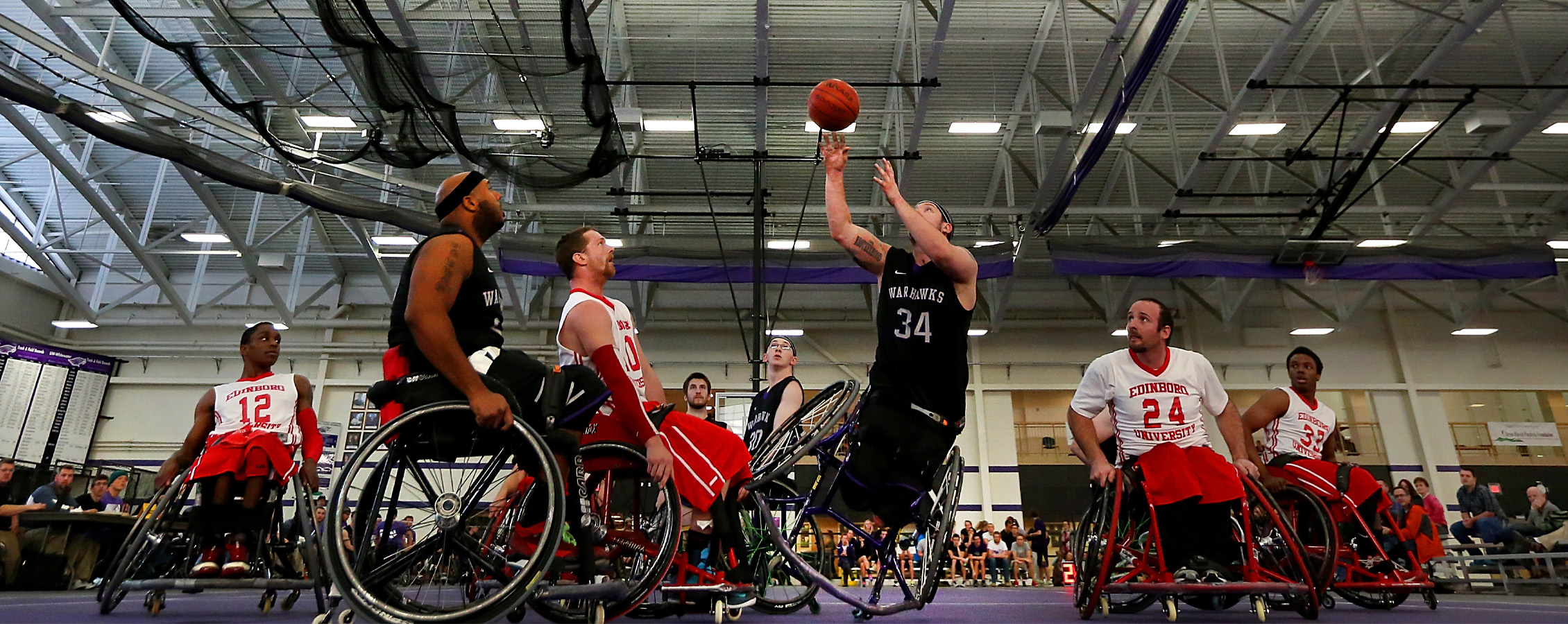 A Warhawk men's wheelchair basketball player shoots the ball.