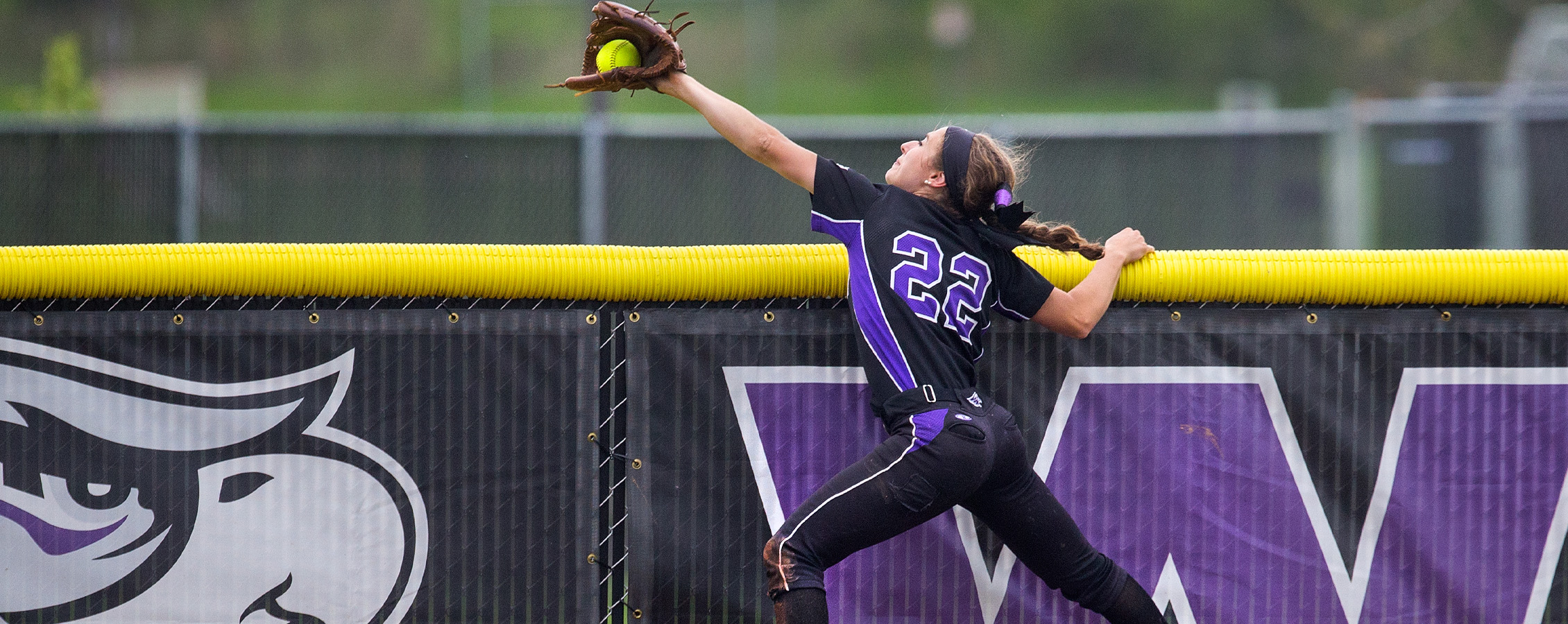 A Warhawk women's basketball player jumps through two opponents to get the basketball.