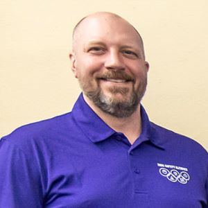 David Vosburgh wears a golf shirt while standing in front of a white wall.