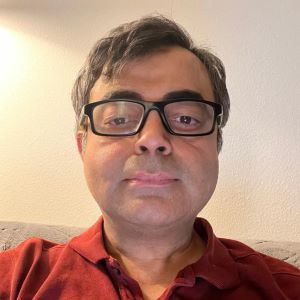Headshot of Aditya Simha wearing a red shirt
