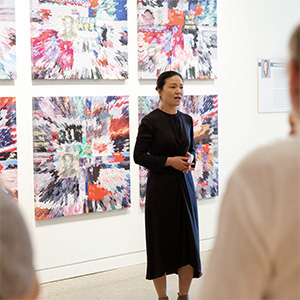 Xiahong Zhang wearing a black dress giving a presentation in front of a group of people