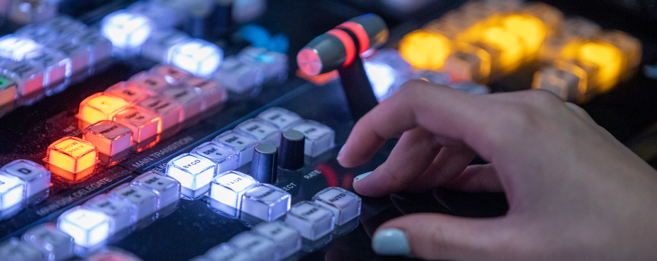 A hand presses buttons on a lit up video control surface.