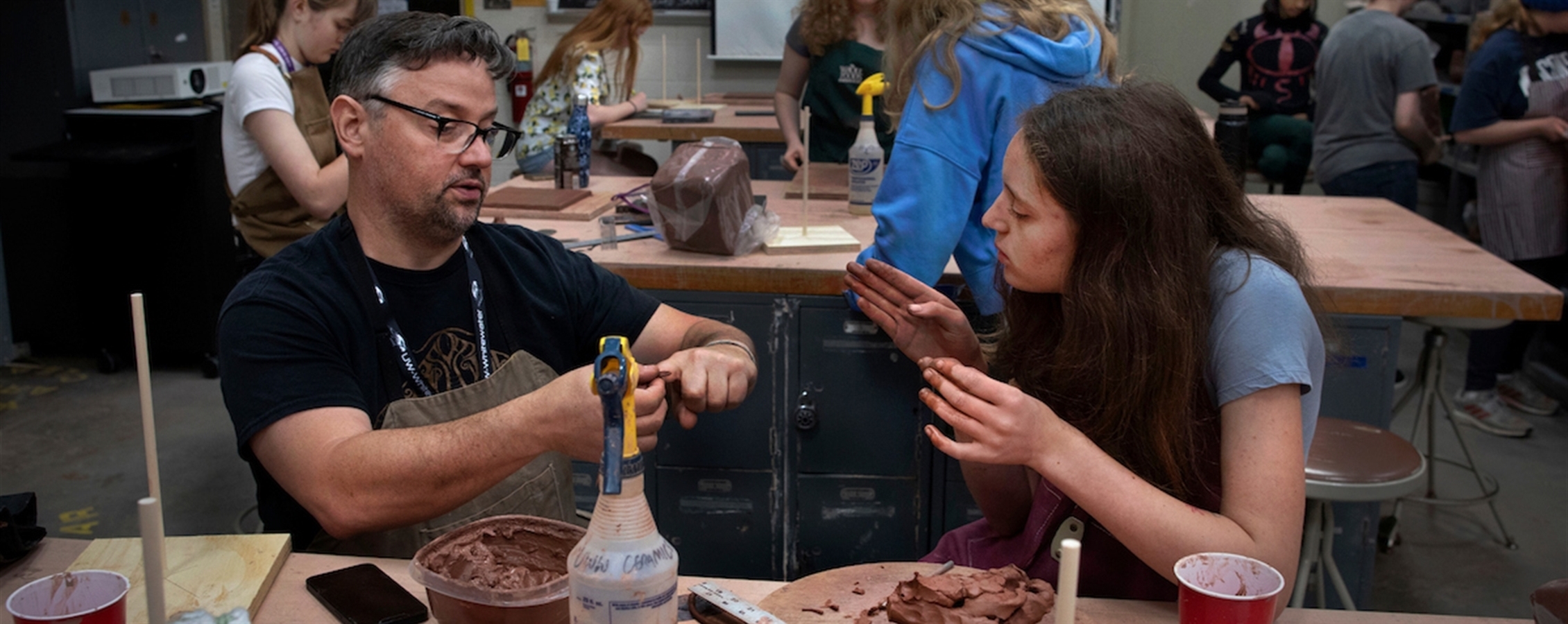 Instructor shows student how to mold clay