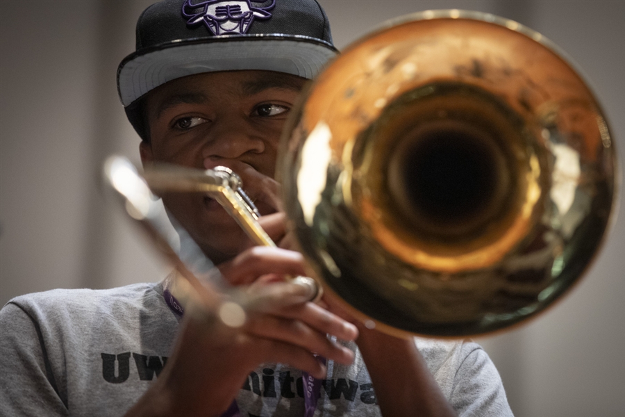 Young trombone player performing during a lesson, viewed from the bell of the instrument.