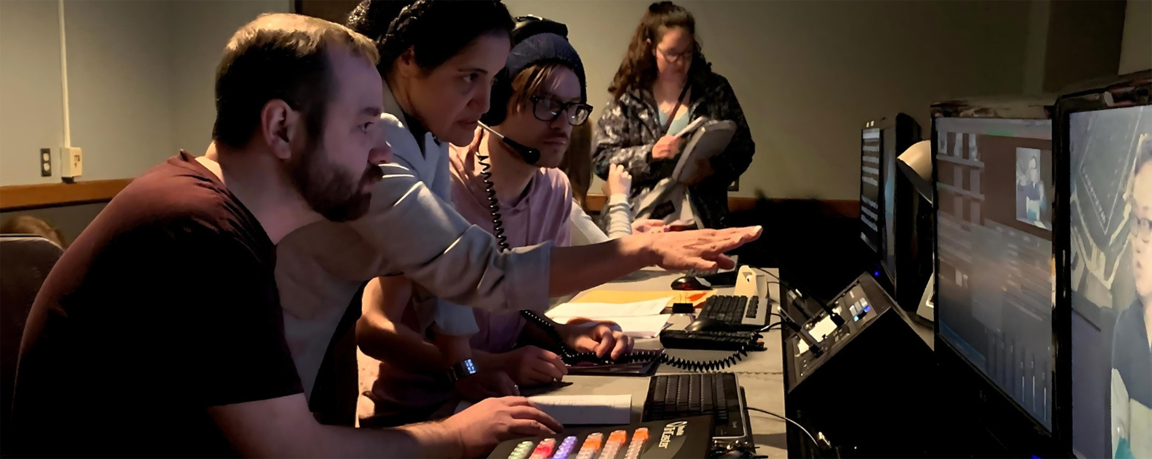 Students and an instructor look at screens while producing news content