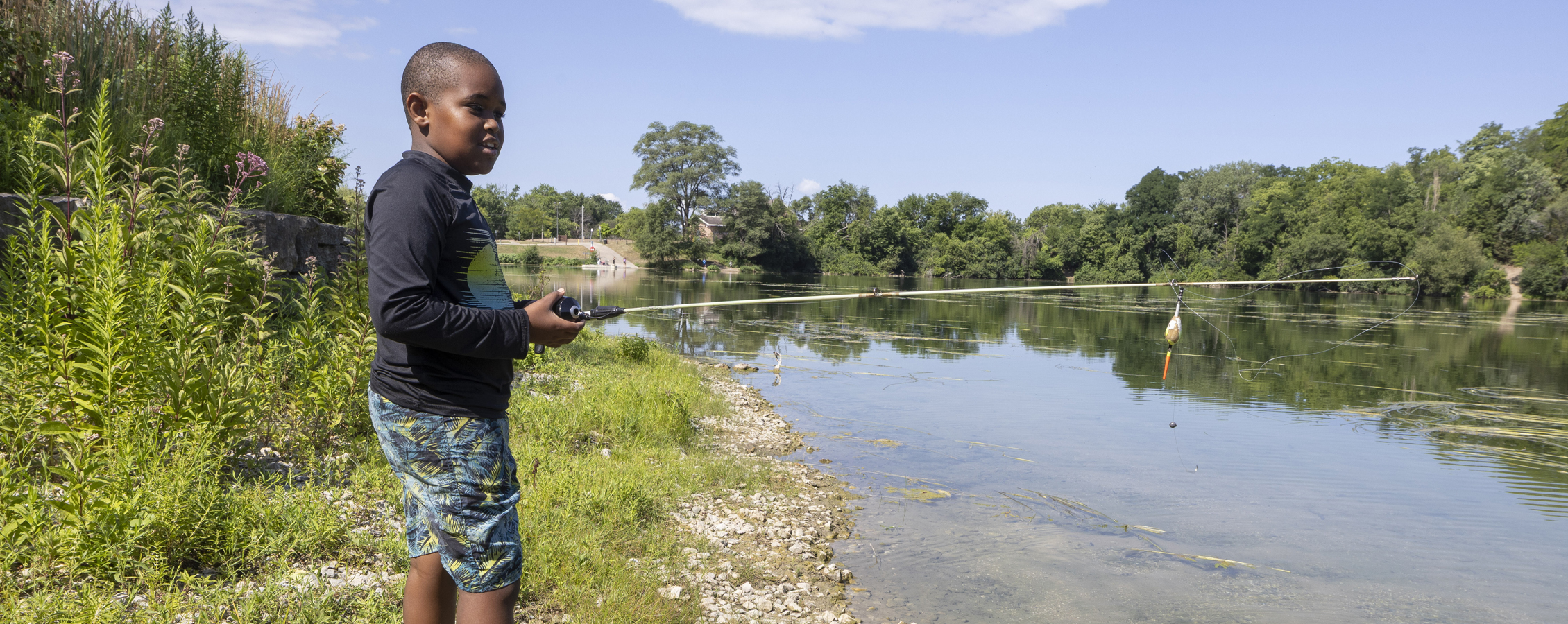 A young boy fishing at a pond.
