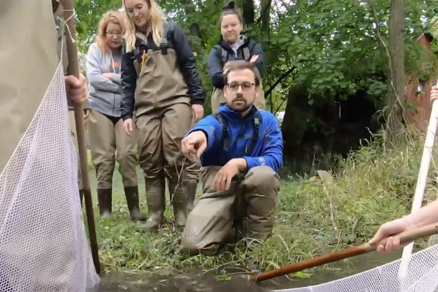 Students watch as an instructor points at a body of water.