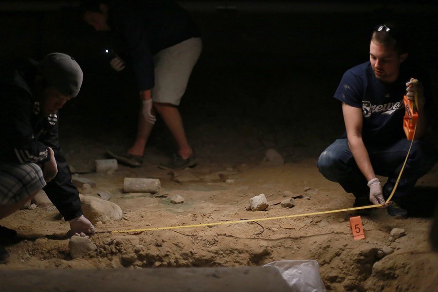 Two students use a tape measure at a mock crime scene.