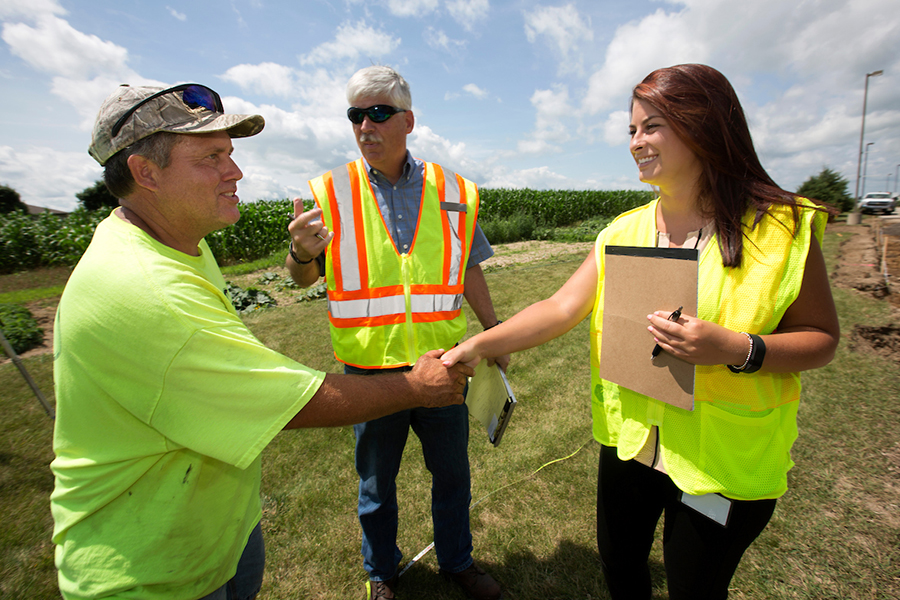 Morgan Drewek shakes hands with the foreman of the construction site being inspected as mentor David Kapitan looks on.