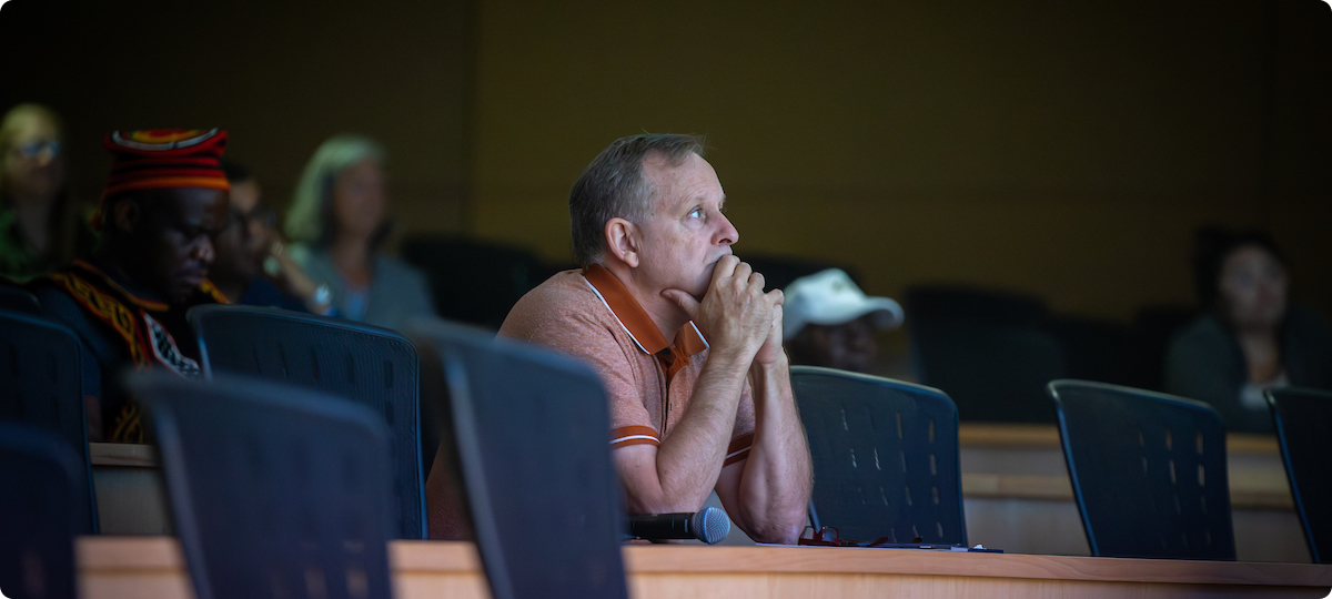Jimmy Peltier studies slide content during Patrice Achu's dissertation defense. Peltier is the second chair of his dissertation