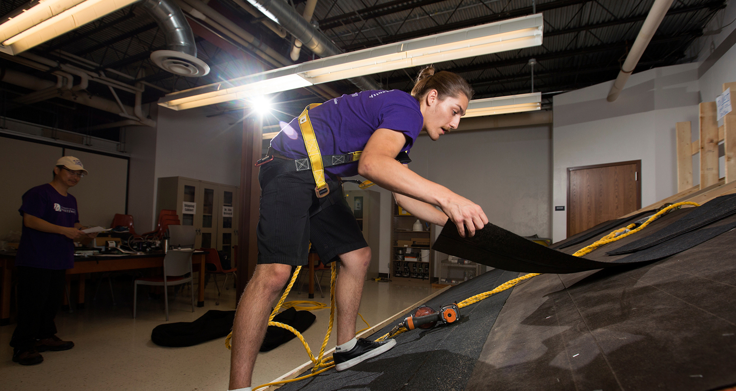 Professor Sang Choi adjusts a safety harness in the Safety Lab in the UW-Whitewater Community Engagement Center