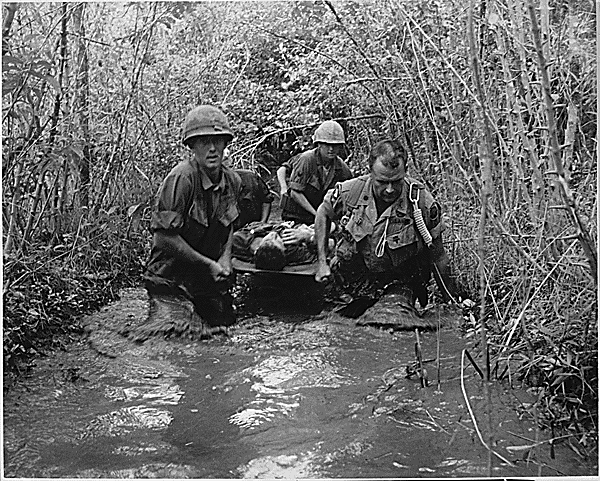 American soldiers carrying a wounded man down a stream
