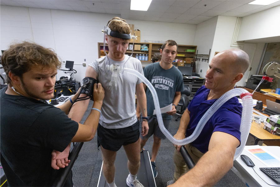A student runs on the treadmill with a tube connecting from her face to a computer.