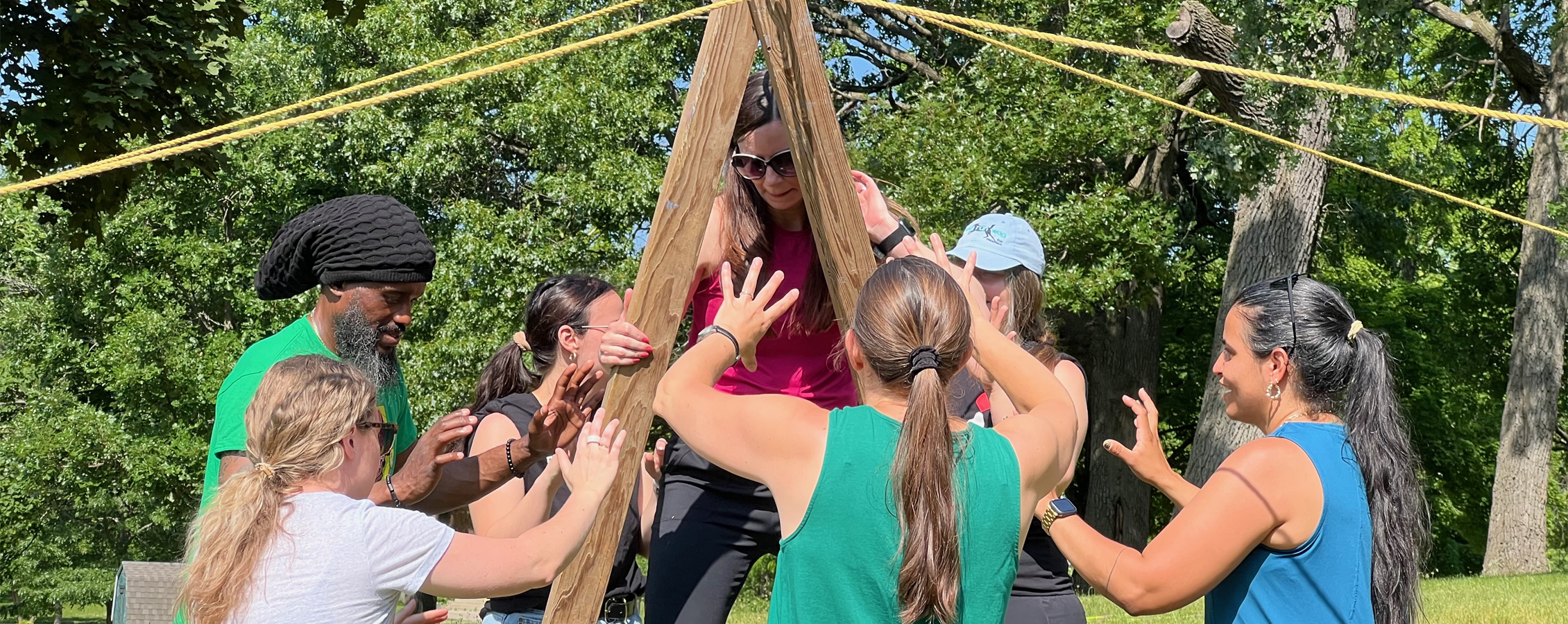 An outdoor team building activity where a group of people are lifting up another person.