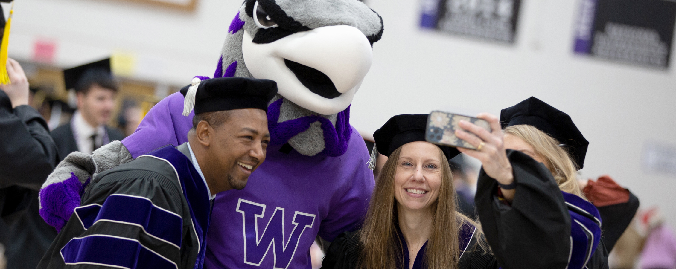 Three graduates pose with Willie for a selfie.