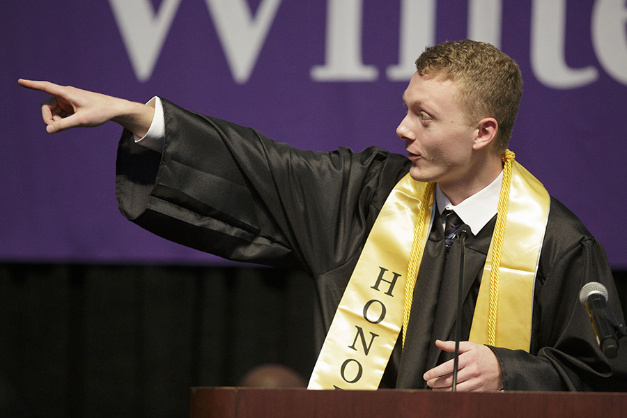 A student fist pumps at the podium during graduation.