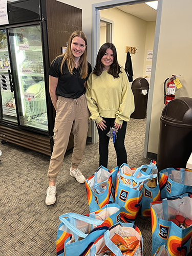 Two students stand next to each other at Aldi and smile.
