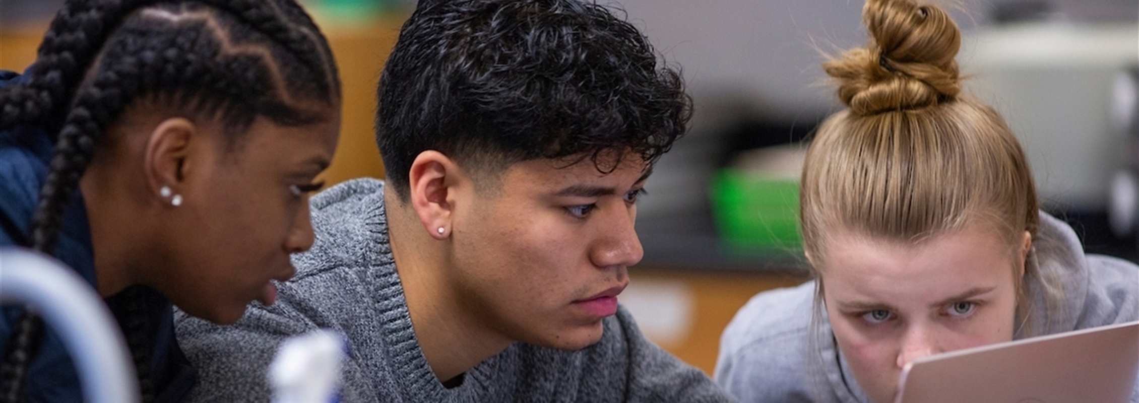 Three students work on a computer.