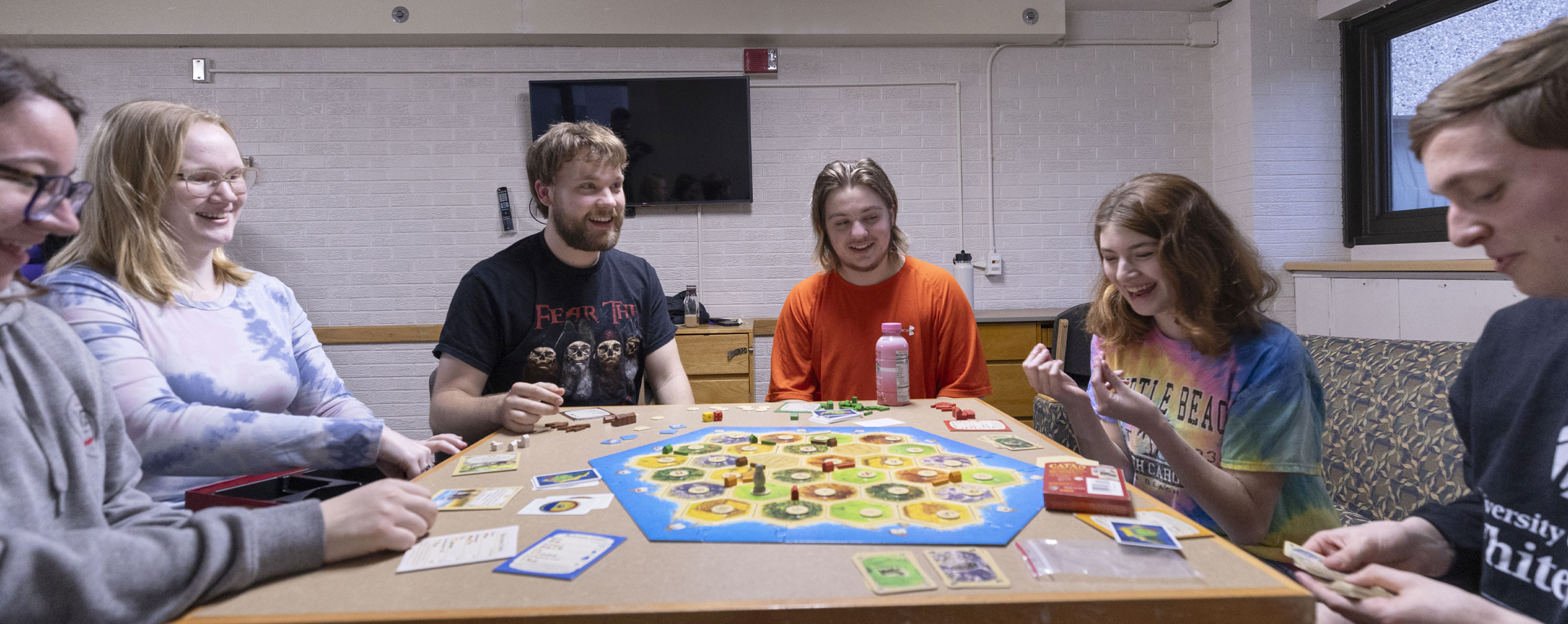 Un grupo de personas se sientan alrededor de una mesa jugando un juego de mesa.