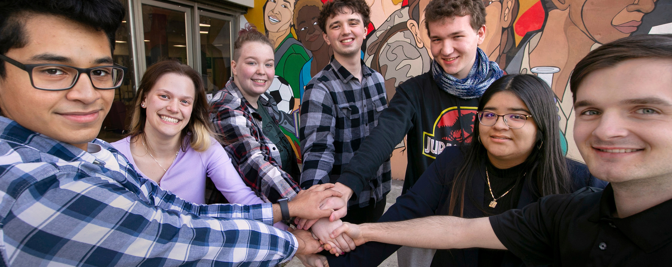 Group of students putting their hands together to celebrate