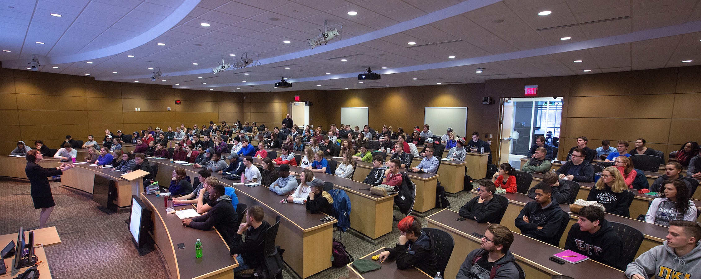 Large lecture hall with dimmed lights filled with UW-Whitewater students