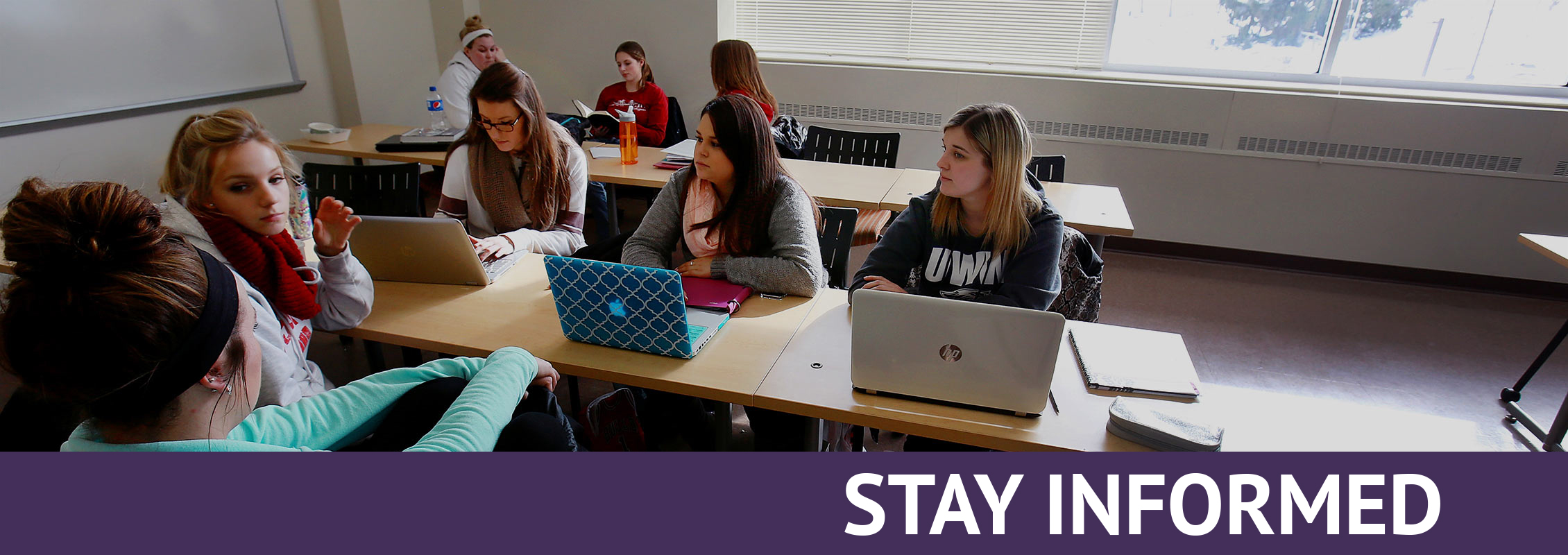 Stay Informed: Students in groups in class, talking and working on laptops