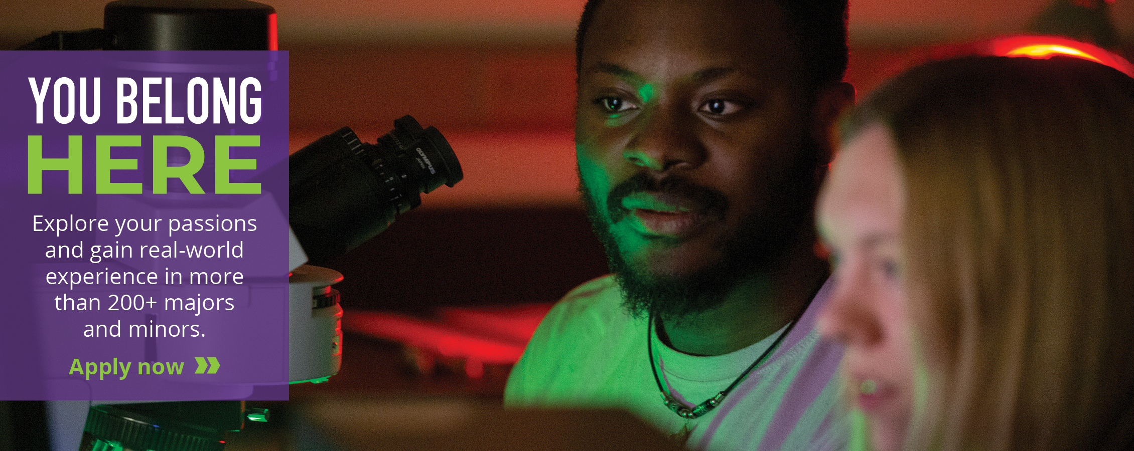 Two students work near a microscope.