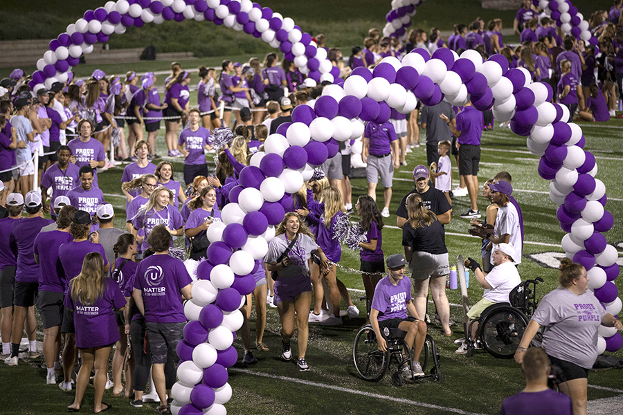 Two students walk past balloons on the football stadium.