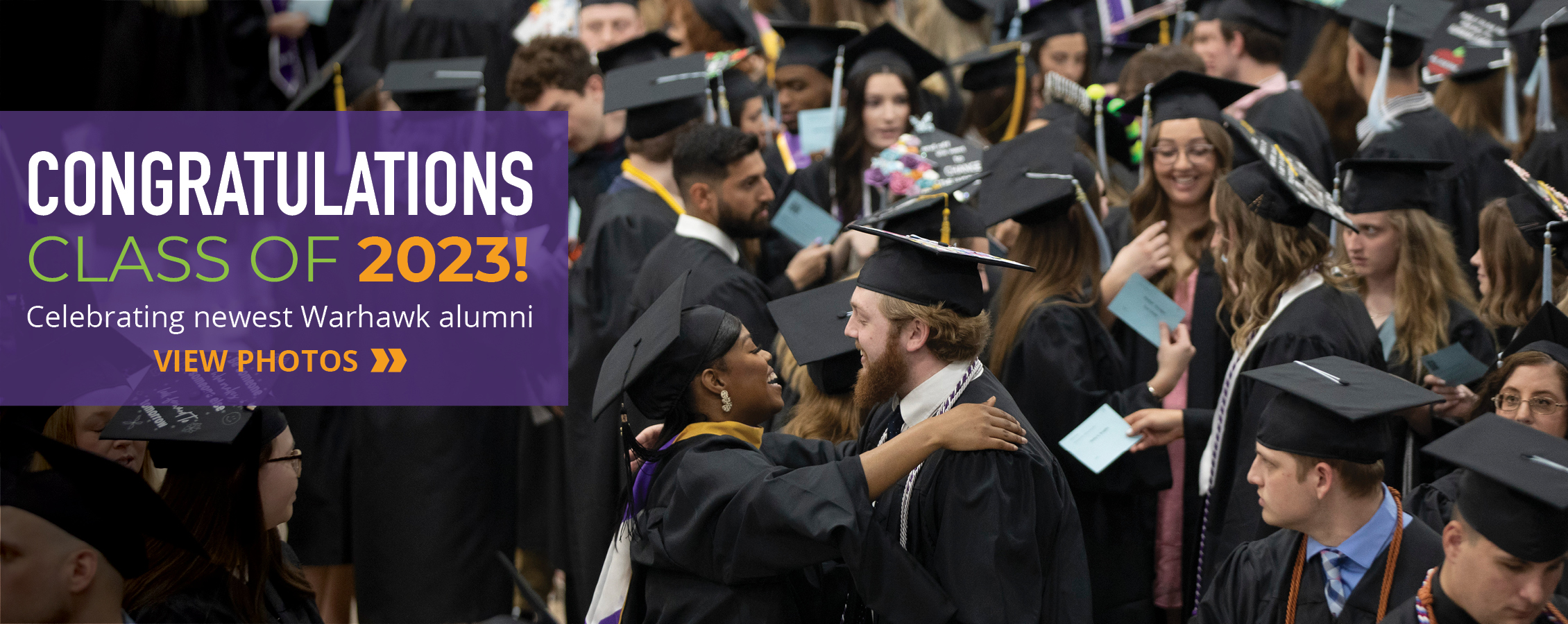 A sea of graduates hug and celebrate together.