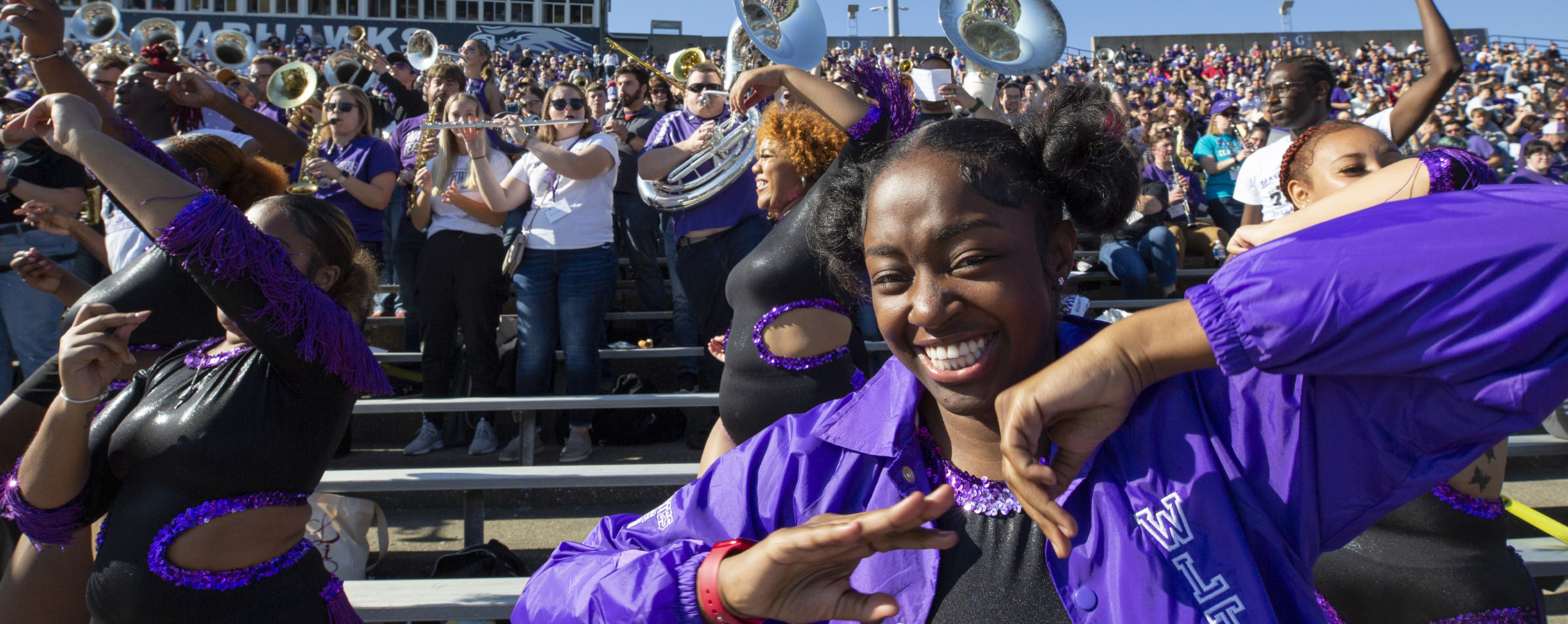 A student smiles and dances in front of the crowd at Perkins Stadium.